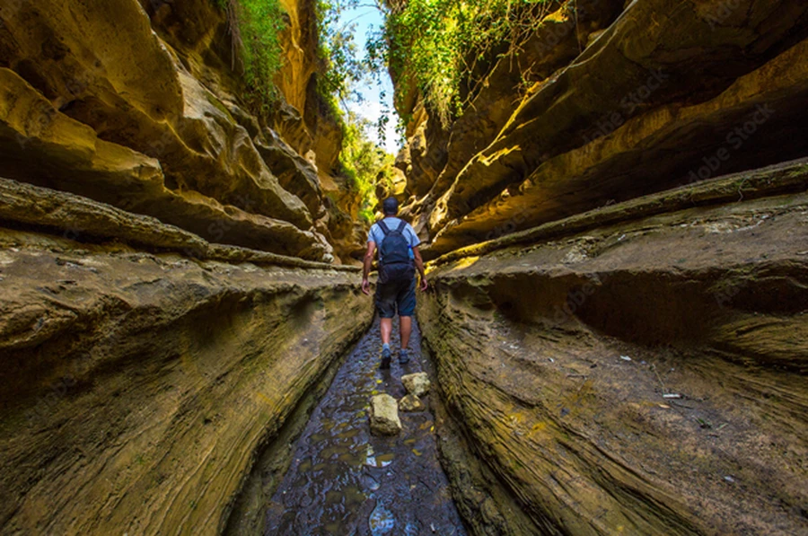 A tourist exploring the Hell’s Gate Gorge in a narrow section of the gorge during a sunny day