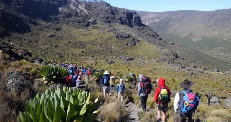 Hikers passing through a lake tarn on Mt Kenya during a Mount Kenya trek on business retreat