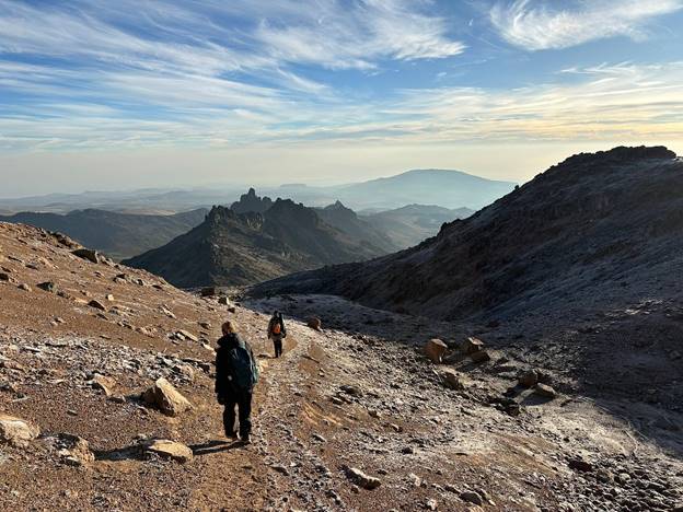 Hikers trekking Mount Kenya on the Sirimon route, dry season sunny day with cirrocumulus clouds