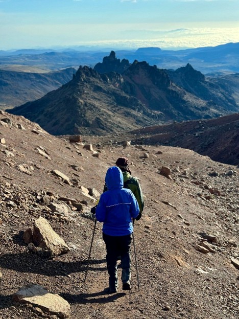 Two hikers on Mount Kenya climb exploring the landscape on a sunny day. One is using trekking poles