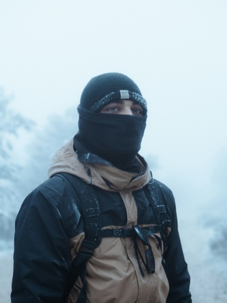 A hiker with a beanie and balaclava for warmth while mountaineering in snow