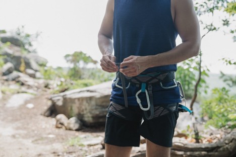 A technical climber in shorts wearing a climbing harness on a rocky Mount Kenya wall