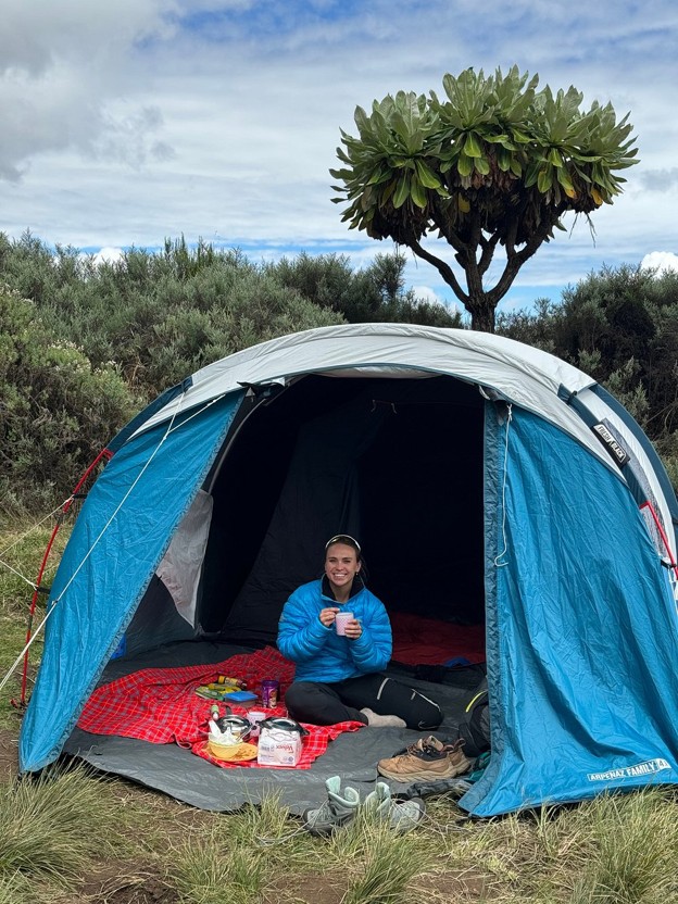 Hiker in her tent enjoying her meal after a Mount Kenya trek, hiking boots and sport shoes taken off