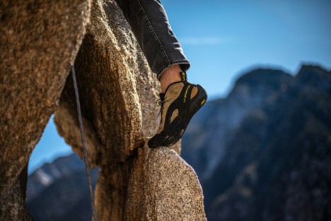 Close-up of a hiker’s foot in climbing shoes gripping steep rock during a technical climb