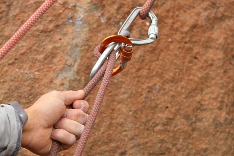 A belay device attached to climbing ropes during a rock-climbing session