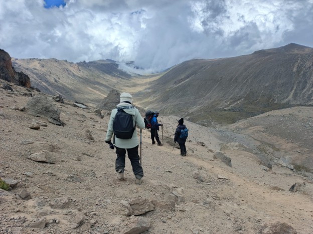 Hikers on Mount Kenya carrying compact daypacks with water bottle and trekking poles