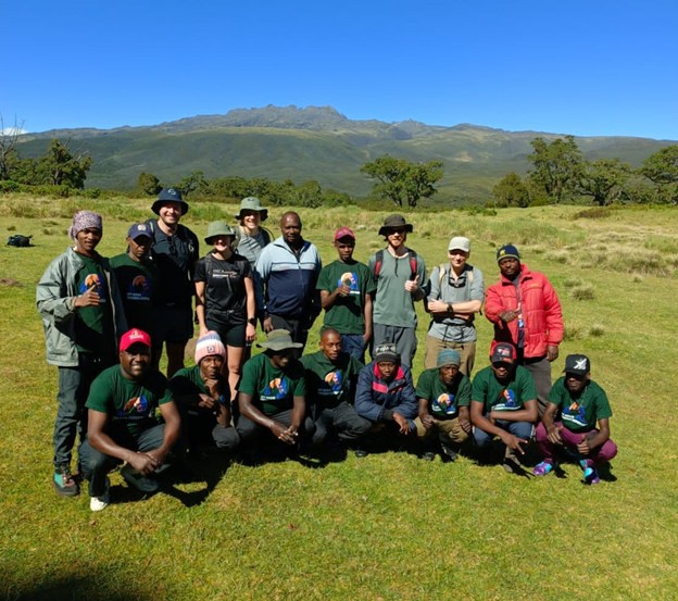 European hikers and MtKenyatrekking staff wearing company-branded t-shirts posing for a group photo