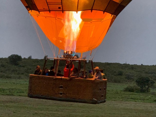 Tourists on a hot air balloon mid-launch from the ground while on safari in Maasai Mara