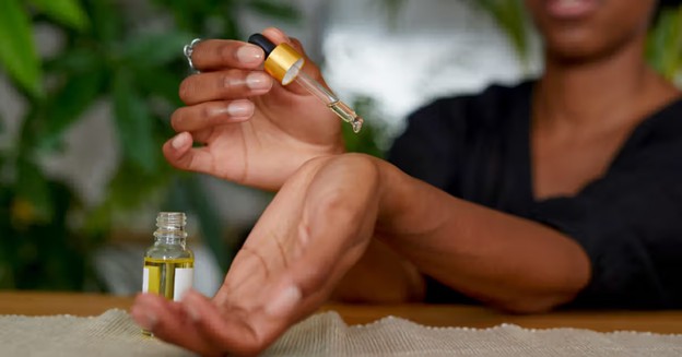 A lady applying insect repellent tincture oil on her skin to keep insects away while outdoor