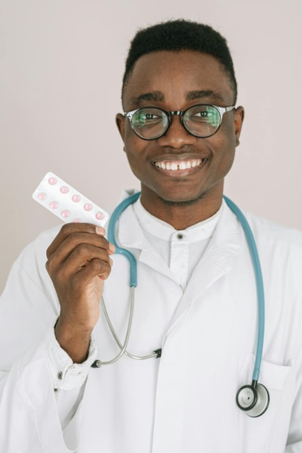 A medical personnel in white labcoat and stethoscope holding tablet medication in bubble packs