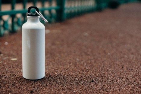 A white reusable water bottle placed on the ground