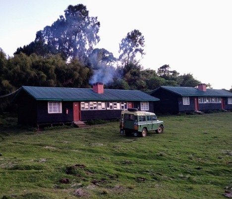 A mountain expedition vehicle parked outside Meru Mount Kenya Bandas resort, with a smoky chimney
