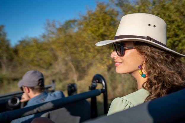 Safari traveller wearing sunglasses while viewing wildlife in Kenya